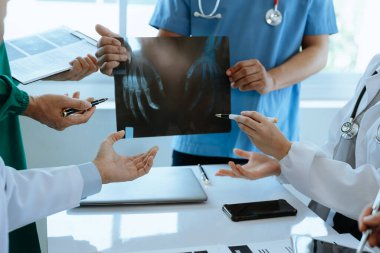 Tıbbi ekip laboratuvar önlüklü ve ameliyat önlüklü doktorlarla bir toplantı yapıyor. Hastaları tartışıyor, internette tıbbi endüstride bilgisayar kullanıyor.