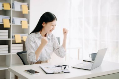 Asyalı iş kadını, modern ofiste dizüstü bilgisayarla çalışan mutlu ve mutlu biri.