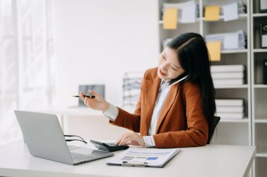 Modern ofiste bilgisayarla konuşan mutlu Asyalı iş kadını.