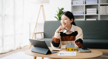Genç emlakçı, evdeki ofiste ve küçük evde tabletle çalışıyor. 