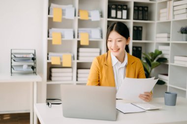 Genç ve çekici Asyalı kadın ve dizüstü bilgisayar evden modern ofise bakıyor. 