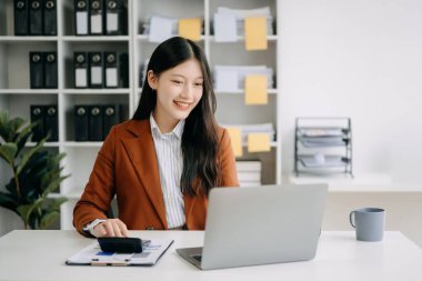 Modern ofiste dizüstü bilgisayarla çalışan Asyalı bir iş kadını.