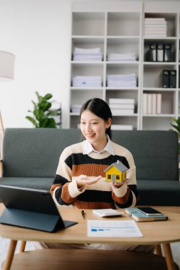 Genç emlakçı, evdeki ofiste ve küçük evde tabletle çalışıyor. 