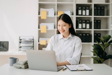 Modern ofiste dizüstü bilgisayarla çalışan Asyalı bir iş kadını.