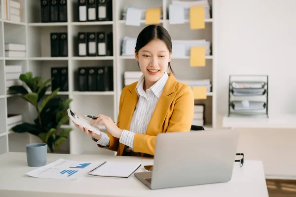 stock image Young attractive Asian woman and laptop working from home, looking at camera at modern office 