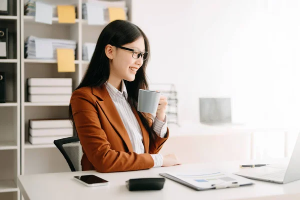 stock image Confident beautiful Asian businesswoman with laptop  and phone at modern office