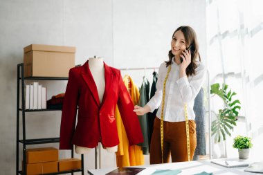 Kafkasyalı genç kadın, ofisinde telefon ve tablet bilgisayarı olan moda tasarımcısı.