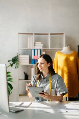 Genç iş kadını tablet ve dizüstü bilgisayarı olan müşterilere online siparişleri kontrol ediyor. İnternetten alışveriş konsepti. Ofiste.