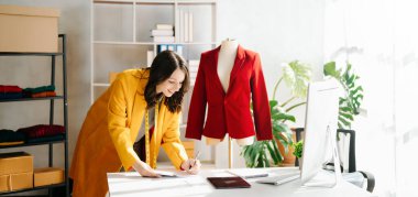 Kafkasyalı genç bir kadın, ofisinde bilgisayar ve tabletle moda tasarımcısı.