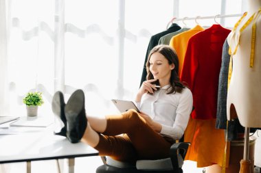 Kafkasyalı genç kadın, ofisinde tablet bilgisayarı olan moda tasarımcısı.