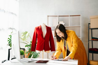Kafkasyalı genç bir kadın, ofisinde bilgisayar ve tabletle moda tasarımcısı.
