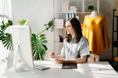 Genç iş kadını tablet ve dizüstü bilgisayarı olan müşterilere online siparişleri kontrol ediyor. İnternetten alışveriş konsepti. Ofiste.