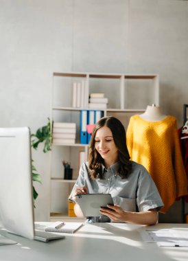 Genç iş kadını tablet ve dizüstü bilgisayarı olan müşterilere online siparişleri kontrol ediyor. İnternetten alışveriş konsepti. Ofiste.