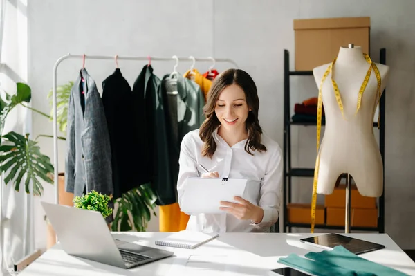 Beyaz kadın, moda tasarımcısı, tablet ve dizüstü bilgisayarı olan. 