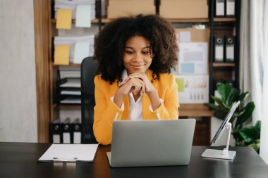 Modern ofiste tablet ve dizüstü bilgisayarla çalışan Afrikalı iş kadını.