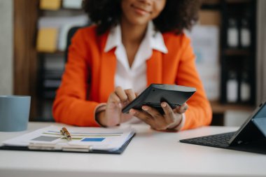 Maliyet, hesap makinesi ve ofisteki tablet bilgisayarla ilgili finansman ile çalışan iş kadını