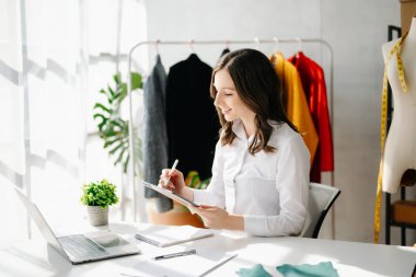 Kafkasyalı genç kadın, dizüstü bilgisayarı olan moda tasarımcısı. 
