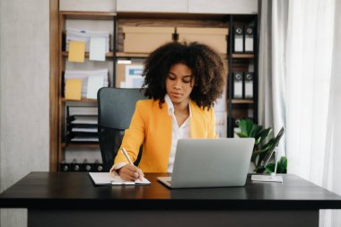 Modern ofiste tablet ve dizüstü bilgisayarla çalışan Afrikalı iş kadını.