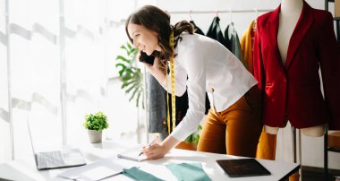 Kafkasyalı genç kadın, tablet, laptop ve akıllı telefonlu moda tasarımcısı..