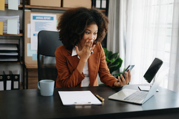 African businesswoman are delighted and happy with  laptop and phone  at the home office