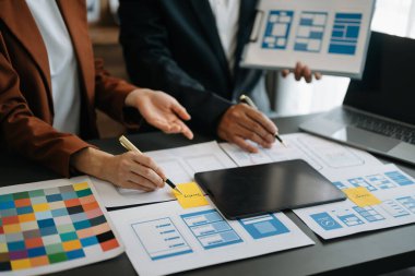  UX geliştiricisi ve ui tasarımcısı modern ofiste müşteri özeti ve renk kodu ile mobil uygulama arayüzü kablo tasarımı hakkında beyin fırtınası yapıyorlar