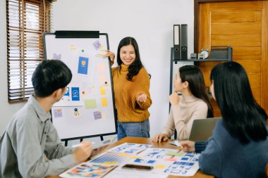 Asyalı iş adamları ofiste toplanıyor. Çalışan beyin fırtınası ve ekip olarak çalışmak, proje planlamak ve tartışmak 
