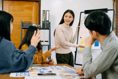 Asyalı iş adamları ofiste toplanıyor. Çalışan beyin fırtınası ve ekip olarak çalışmak, proje planlamak ve tartışmak 