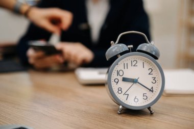 Masadaki çalar saat. İş kadını ofis binasında ya da gece evde çalışıyor. 