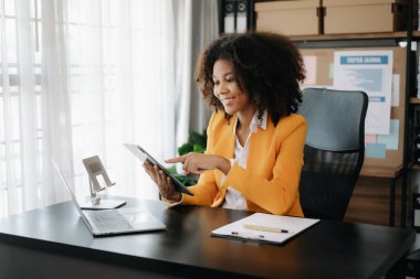 Modern ofiste tablet ve dizüstü bilgisayarla çalışan Afrikalı iş kadını.