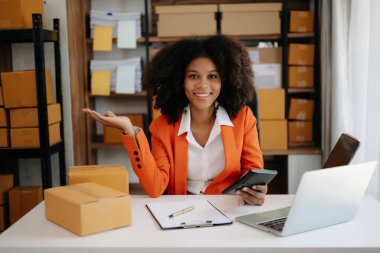 Başlangıçta küçük işletme KOBİ 'si, Girişimci sahibi Afrikalı kadın ev ofisinde paket ürün kutularını hazırlamak için online alışveriş siparişi alıyor ve kontrol ediyor