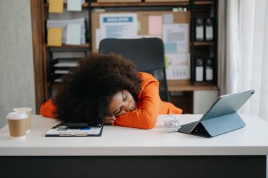 Afrikalı iş kadını, modern ofiste tablet üzerinde çalıştığı için stresli, sıkılmış ve aşırı düşünüyor.