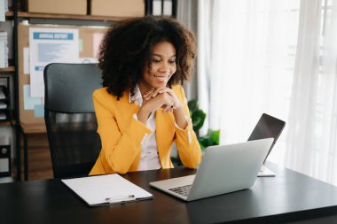 Modern ofiste tablet ve dizüstü bilgisayarla çalışan Afrikalı iş kadını.