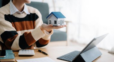 Emlak komisyoncusu, ev kredisi teklifiyle ilgili karar veren imza anlaşmasını, ev modelini, ev kredisini sunar ve müşteriye danışmanlık yapar.