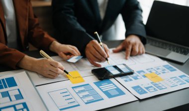  UX geliştiricisi ve ui tasarımcısı modern ofiste müşteri özeti ve renk kodu ile mobil uygulama arayüzü kablo tasarımı hakkında beyin fırtınası yapıyorlar