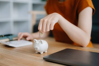 Asyalı kadın ve domuz kumbarası ve hesap makinesi iş, finans, tasarruf ve emlak yatırım konsepti için masada. ev ofisinde.