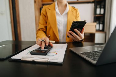 Telefonlu bilgisayar ve hesap makinesine güvenen bir kadın