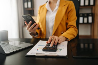 Telefonlu bilgisayar ve hesap makinesine güvenen bir kadın