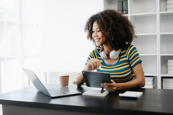 Stock image  Female student, African girl sitting at the desk using laptop 