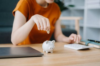 Asyalı kadın ve domuz kumbarası iş, finans, tasarruf ve emlak yatırım konsepti için masada.