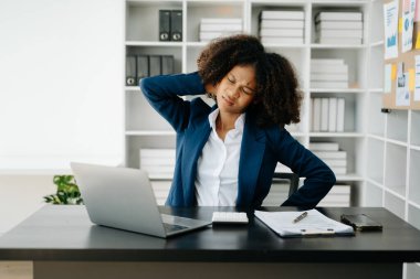 Ofis masasında uzun bir gün geçirdikten sonra boynu ağrıyan genç Afrikalı iş kadını. ofis sendromu kavramı