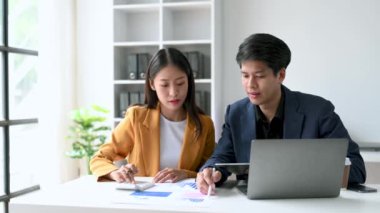 Ofiste konuşan ve dizüstü bilgisayar kullanan iki iş adamı..