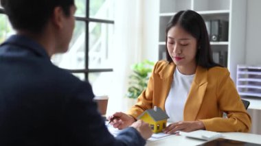Real estate broker agent presenting and consult to customer to decision-making sign insurance form agreement, home model, concerning mortgage loan offer