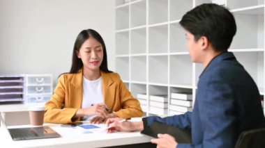 Ofiste konuşan ve dizüstü bilgisayar kullanan iki iş adamı..