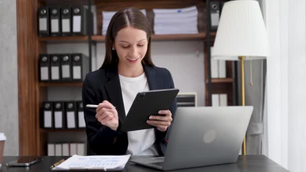 創造的なオフィスの机の上にデジタルタブレットやラップトップを持つ自信のビジネスの専門家の女性 — ストック動画