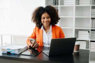 Modern ofiste çalışan telefon, tablet bilgisayar ve bilgisayarlı genç Afrikalı kadın.