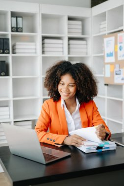 Modern ofiste çalışan tabletli ve bilgisayarlı genç Afrikalı kadın.