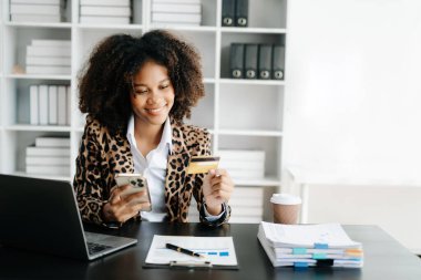 Afrikalı Kadın mobil ödemeler için akıllı telefon kullanıyor online alışveriş, omni kanalı, masada oturuyor, sanal simge grafik arayüzü 