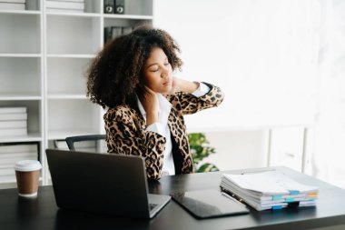 Ofis masasında uzun bir gün geçirdikten sonra boynu ağrıyan genç Afrikalı iş kadını. ofis sendromu kavramı
