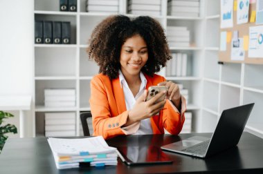 Modern ofiste çalışan telefon, tablet bilgisayar ve bilgisayarlı genç Afrikalı kadın.
