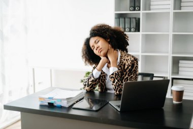 Ofis masasında uzun bir gün geçirdikten sonra boynu ağrıyan genç Afrikalı iş kadını. ofis sendromu kavramı